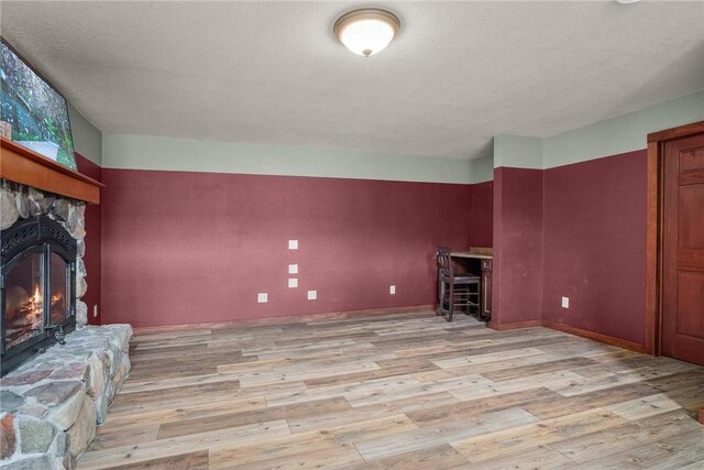 2832 130th Ave, Glenwood City, WI 54013 - unfurnished living room with light wood-type flooring, a stone fireplace, and a textured ceiling