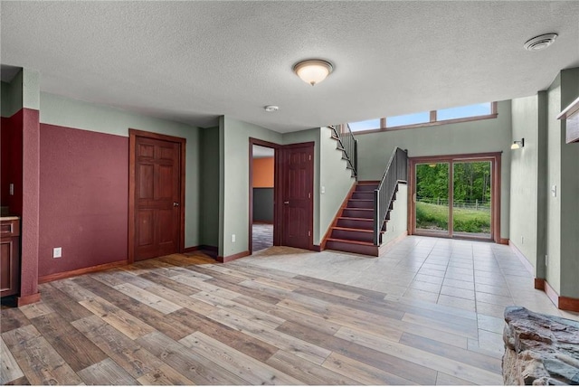 2832 130th Ave, Glenwood City, WI 54013 - unfurnished living room with light wood finished floors, stairway, and a textured ceiling
