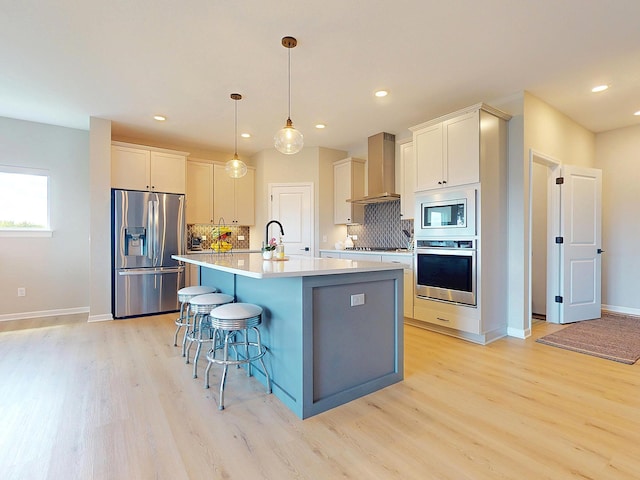 15613 116th Ave N, Dayton, MN 55369 - kitchen with appliances with stainless steel finishes, wall chimney range hood, light wood-type flooring, tasteful backsplash, and recessed lighting