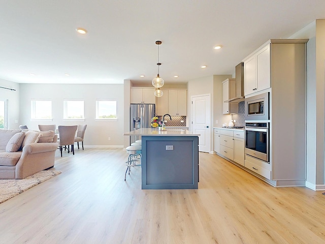 15613 116th Ave N, Dayton, MN 55369 - kitchen with appliances with stainless steel finishes, open floor plan, a breakfast bar, wall chimney range hood, and light wood-type flooring
