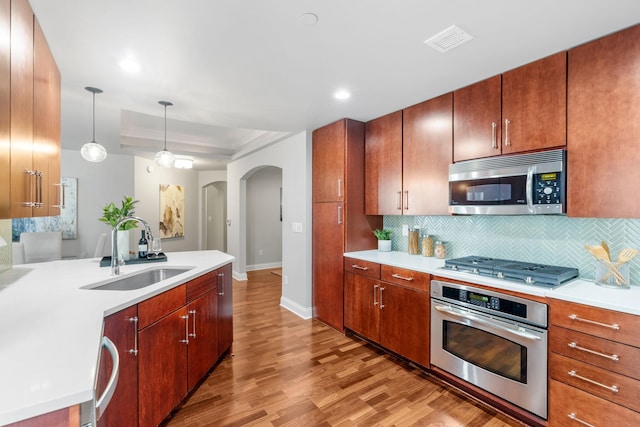 100 3rd Ave S Unit 805, Minneapolis, MN 55401 - kitchen featuring stainless steel appliances, arched walkways, light wood-style flooring, backsplash, and light countertops