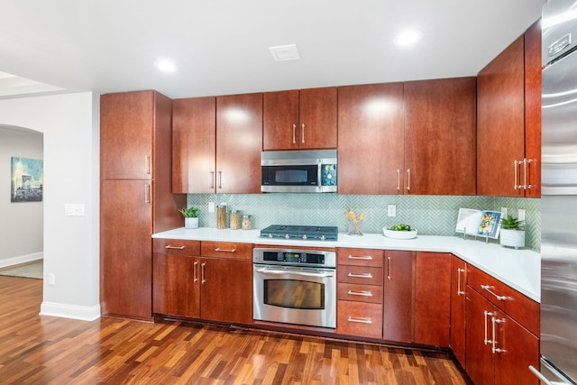 100 3rd Ave S Unit 805, Minneapolis, MN 55401 - kitchen featuring appliances with stainless steel finishes, dark wood-style floors, light countertops, arched walkways, and backsplash