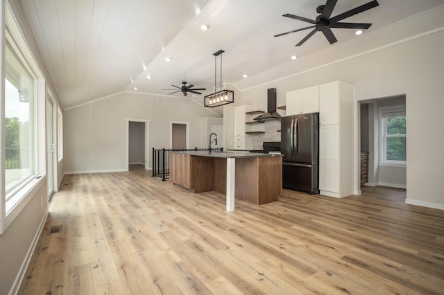 7591 Lake Ida Way NW, Alexandria, MN 56308 - kitchen featuring freestanding refrigerator, ceiling fan, wall chimney exhaust hood, open floor plan, and light wood-style floors