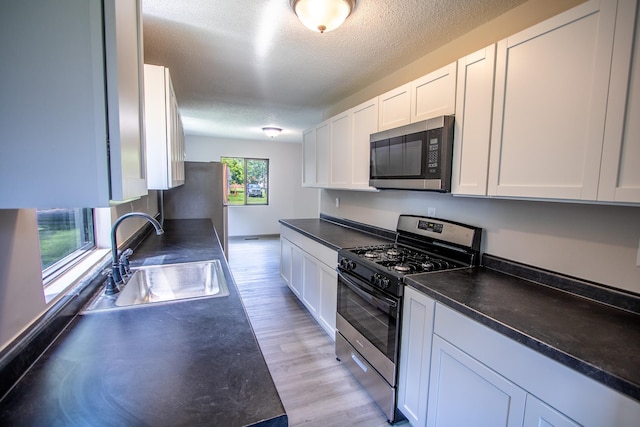 422 Park Ave, Sandstone, MN 55072 - kitchen with appliances with stainless steel finishes, dark countertops, white cabinets, light wood finished floors, and a textured ceiling