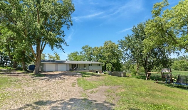 19421 708th Ave, Dassel, MN 55325 - view of grassy yard featuring a trampoline, a garage, and dirt driveway