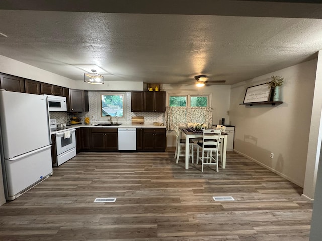 815 6th St N, New Ulm, MN 56073 - kitchen featuring white appliances, dark brown cabinets, wood finished floors, backsplash, and a textured ceiling