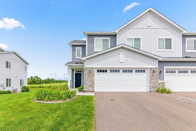 10070 32nd St NE, Saint Michael, MN 55376 - view of front of property with stone siding, a front yard, asphalt driveway, a garage, and board and batten siding