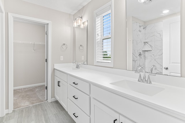 10070 32nd St NE, Saint Michael, MN 55376 - bathroom with double vanity, a marble finish shower, a walk in closet, and wood finished floors