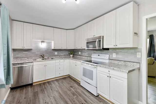 219 10th Ave E, Fargo, ND 58078 - kitchen featuring appliances with stainless steel finishes, light wood-style flooring, tasteful backsplash, and white cabinetry