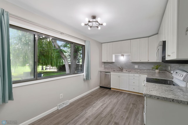 219 10th Ave E, Fargo, ND 58078 - kitchen with white cabinets, appliances with stainless steel finishes, tasteful backsplash, and light wood-type flooring