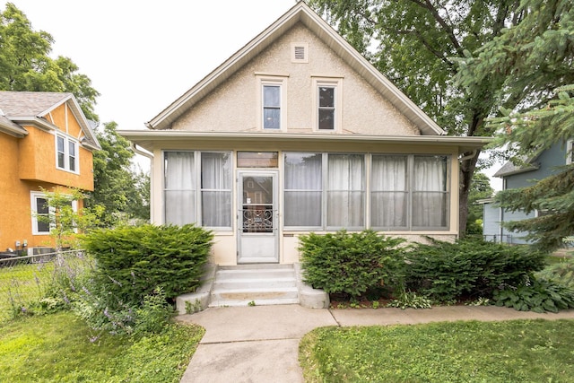 3331 34th Ave S, Minneapolis, MN 55406 - bungalow with entry steps, a sunroom, and stucco siding