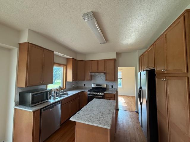 1355 Butterfly Ln, Spring Lake Twp, MN 55352 - kitchen featuring stainless steel appliances, a kitchen island, under cabinet range hood, dark wood-style floors, and a textured ceiling