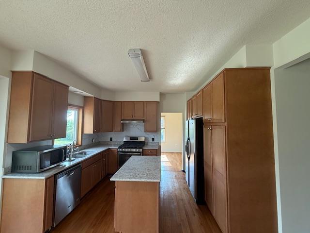 1355 Butterfly Ln, Spring Lake Twp, MN 55352 - kitchen with stainless steel appliances, a kitchen island, dark wood-type flooring, under cabinet range hood, and a textured ceiling