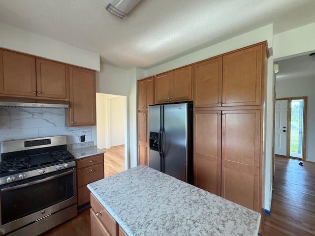 1355 Butterfly Ln, Spring Lake Twp, MN 55352 - kitchen with appliances with stainless steel finishes, under cabinet range hood, dark wood-style flooring, backsplash, and a textured ceiling