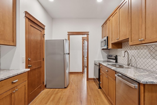 704-706 Holly Ave, Saint Paul, MN 55104 - kitchen featuring appliances with stainless steel finishes, tasteful backsplash, light wood-style floors, light stone countertops, and brown cabinets