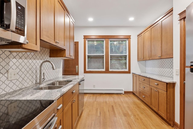 704-706 Holly Ave, Saint Paul, MN 55104 - kitchen featuring appliances with stainless steel finishes, a baseboard heating unit, light wood-style floors, light stone countertops, and tasteful backsplash