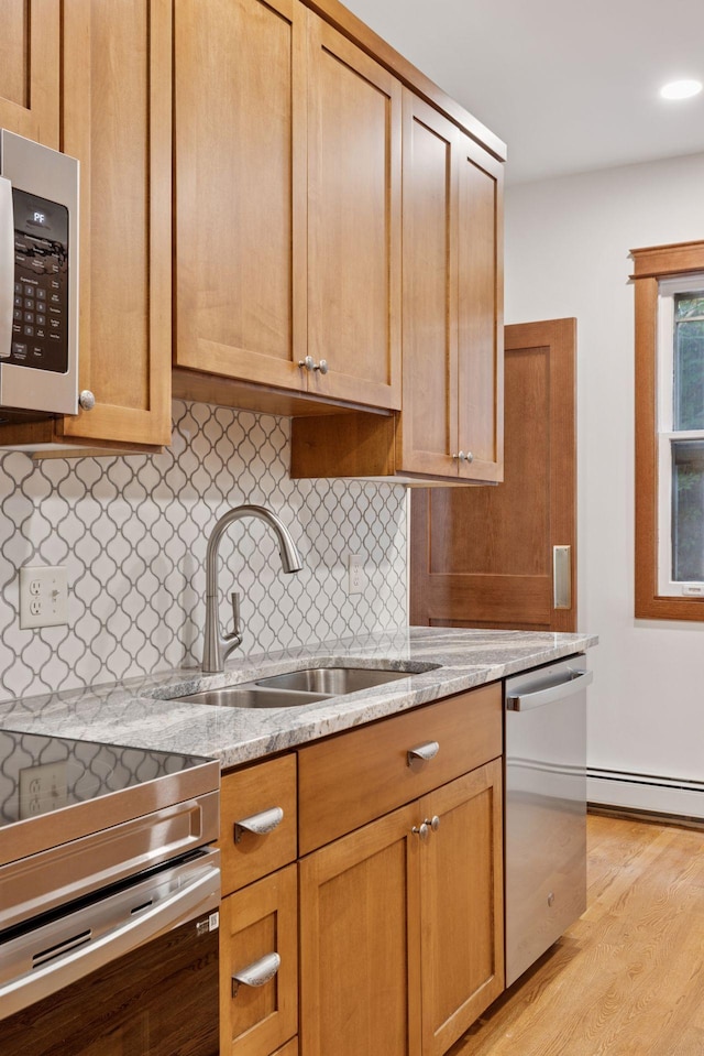 704-706 Holly Ave, Saint Paul, MN 55104 - kitchen featuring stainless steel appliances, a baseboard radiator, light wood-type flooring, tasteful backsplash, and light stone counters