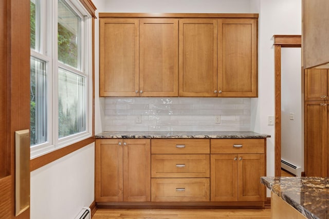 704-706 Holly Ave, Saint Paul, MN 55104 - kitchen with baseboard heating, decorative backsplash, dark stone counters, and healthy amount of natural light