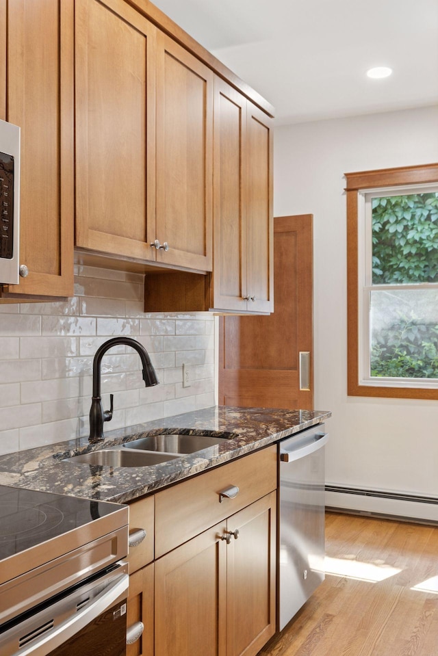 704-706 Holly Ave, Saint Paul, MN 55104 - kitchen featuring baseboard heating, appliances with stainless steel finishes, tasteful backsplash, light wood-style flooring, and dark stone countertops