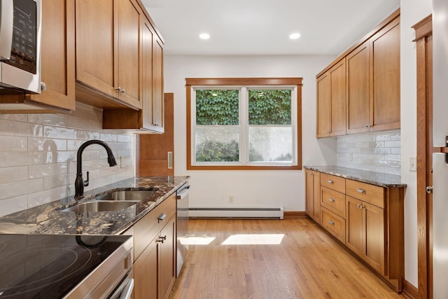 704-706 Holly Ave, Saint Paul, MN 55104 - kitchen with baseboard heating, light wood-style floors, dark stone counters, dishwasher, and decorative backsplash