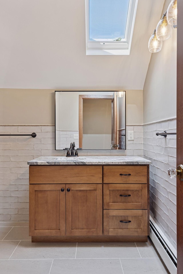 704-706 Holly Ave, Saint Paul, MN 55104 - bathroom with baseboard heating, a skylight, vanity, tile patterned flooring, and a wainscoted wall