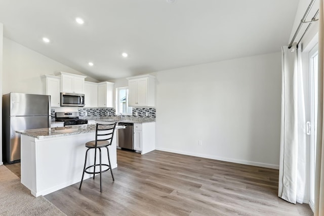 39685 Fallbrook Ave, North Branch, MN 55056 - kitchen with appliances with stainless steel finishes, a kitchen island, backsplash, vaulted ceiling, and light wood-style flooring
