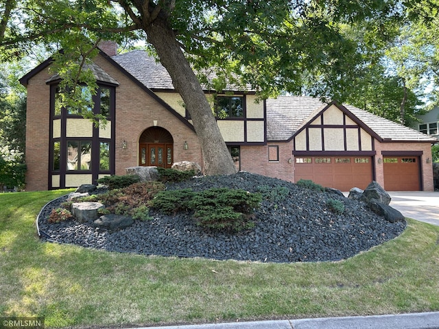 317 Oakwood Ter, Vadnais Heights, MN 55127 - tudor home with a garage, brick siding, a front lawn, concrete driveway, and french doors