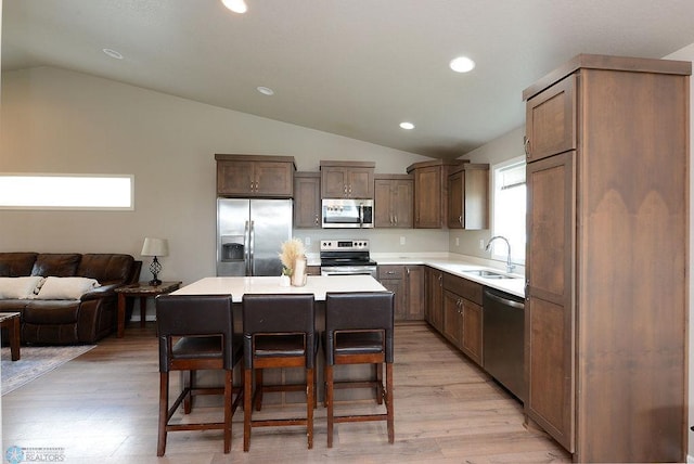 8037 Goldfinch Dr, Horace, ND 58047 - kitchen with stainless steel appliances, vaulted ceiling, a breakfast bar area, light wood-style flooring, and light countertops