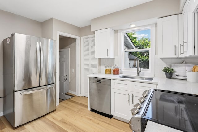 5912 Bartlett Blvd, Mound, MN 55364 - kitchen with appliances with stainless steel finishes, light countertops, white cabinetry, decorative backsplash, and light wood finished floors