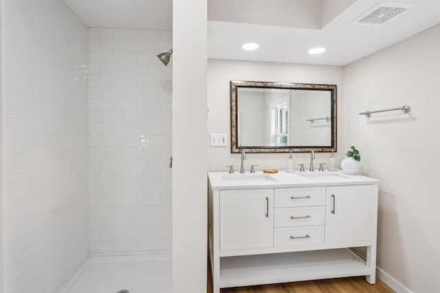 5912 Bartlett Blvd, Mound, MN 55364 - full bathroom featuring a tile shower, double vanity, recessed lighting, and wood finished floors