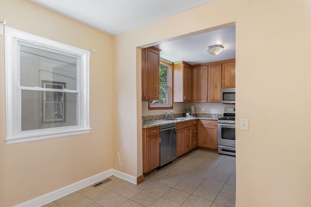 4340 Oakland Ave, Minneapolis, MN 55407 - kitchen featuring stainless steel appliances, light tile patterned floors, brown cabinets, and light stone counters