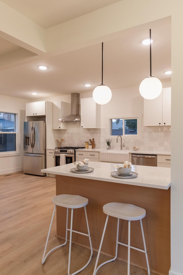212 Diamond Lake Rd, Minneapolis, MN 55419 - kitchen featuring stainless steel appliances, wall chimney range hood, a kitchen bar, tasteful backsplash, and light countertops