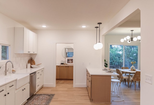 212 Diamond Lake Rd, Minneapolis, MN 55419 - kitchen with stainless steel dishwasher, light wood finished floors, a peninsula, a kitchen breakfast bar, and white cabinetry