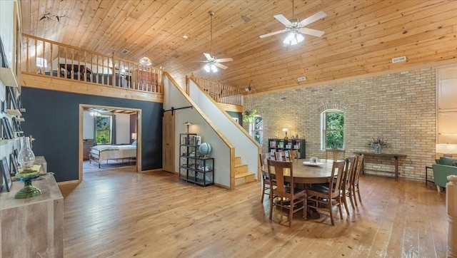8825 Greeley Loop, Royalton Twp, MN 55006 - dining room with a high ceiling, brick wall, a ceiling fan, stairway, and hardwood / wood-style flooring