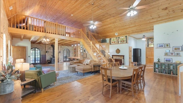 8825 Greeley Loop, Royalton Twp, MN 55006 - dining space with ceiling fan, a wood stove, hardwood / wood-style floors, stairway, and a towering ceiling