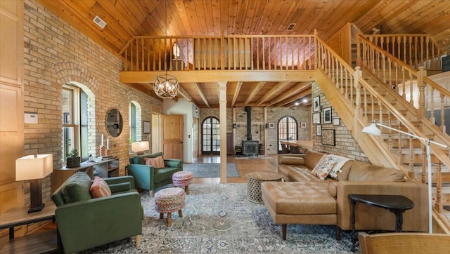 8825 Greeley Loop, Royalton Twp, MN 55006 - living area featuring brick wall, a wood stove, a high ceiling, stairway, and wooden ceiling