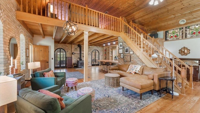 8825 Greeley Loop, Royalton Twp, MN 55006 - living room featuring brick wall, wood-type flooring, a wood stove, a towering ceiling, and stairway