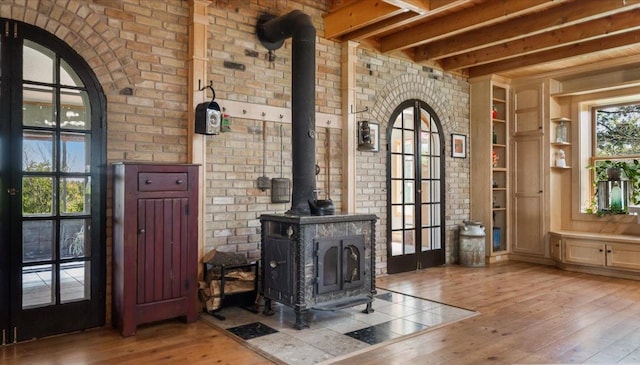 8825 Greeley Loop, Royalton Twp, MN 55006 - living room featuring a wood stove, hardwood / wood-style flooring, built in shelves, brick wall, and beamed ceiling