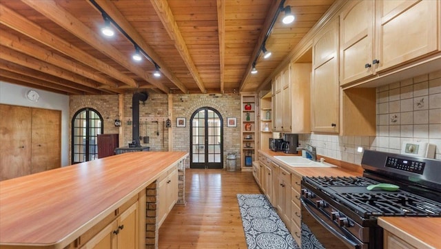 8825 Greeley Loop, Royalton Twp, MN 55006 - kitchen with stainless steel range with gas stovetop, butcher block counters, a wood stove, rail lighting, and light wood-style floors