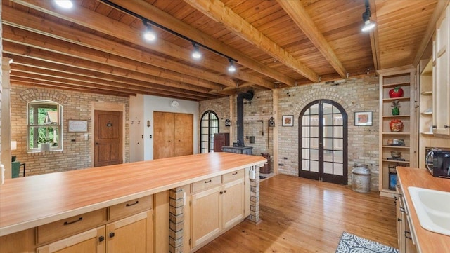 8825 Greeley Loop, Royalton Twp, MN 55006 - kitchen featuring wooden counters, brick wall, a wood stove, french doors, and rail lighting
