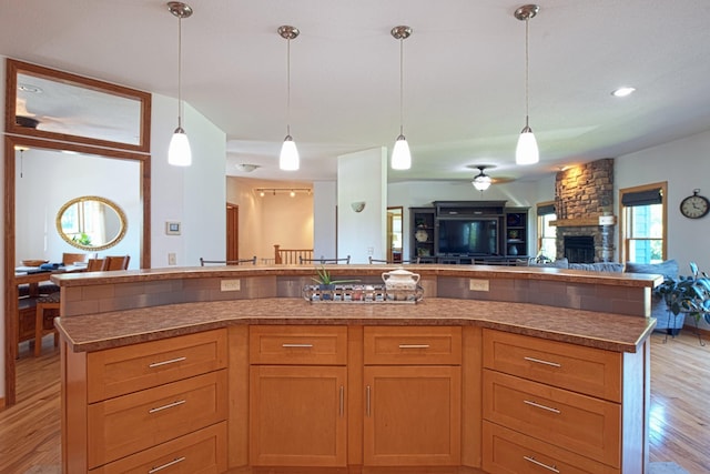 10199 330th St W, Northfield, MN 55057 - kitchen with open floor plan, light wood finished floors, a stone fireplace, ceiling fan, and hanging light fixtures