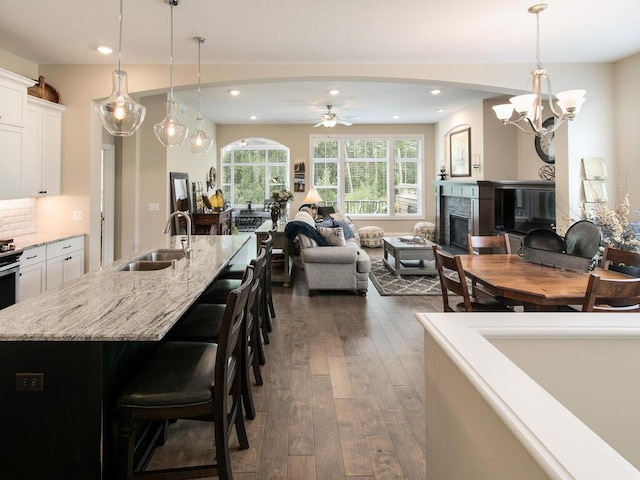 13324 Hillsboro Ave, Savage, MN 55378 - kitchen featuring open floor plan, dark wood-style floors, white cabinets, ceiling fan, and a breakfast bar area