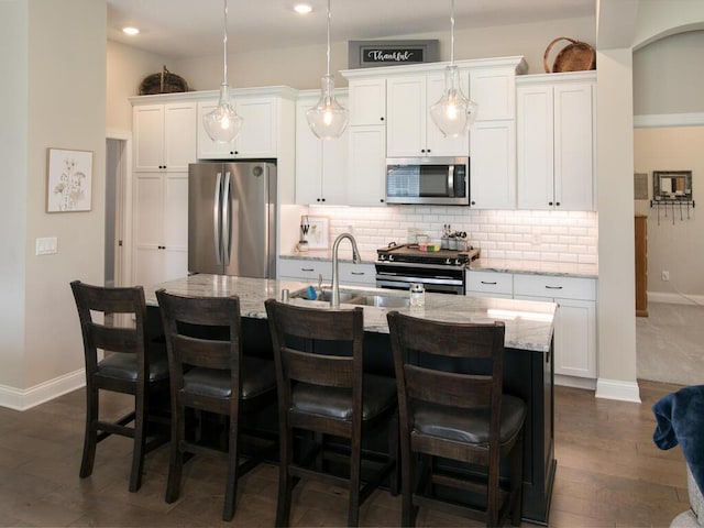 13324 Hillsboro Ave, Savage, MN 55378 - kitchen with stainless steel appliances, an island with sink, tasteful backsplash, white cabinets, and dark wood-style flooring