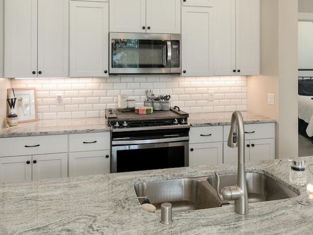 13324 Hillsboro Ave, Savage, MN 55378 - kitchen featuring stainless steel appliances, white cabinetry, decorative backsplash, and light stone countertops