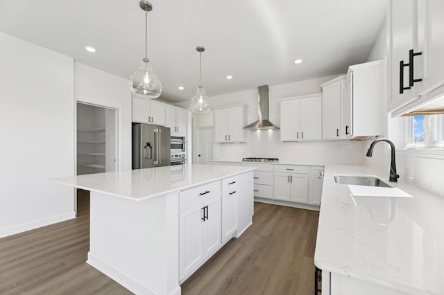 9863 49th St NE, Saint Michael, MN 55376 - kitchen featuring a center island, wood finished floors, wall chimney exhaust hood, stainless steel appliances, and white cabinetry