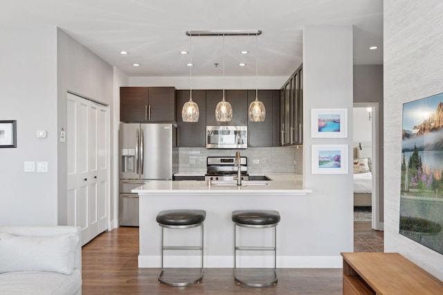 929 Portland Ave Unit 2510, Minneapolis, MN 55404 - kitchen featuring stainless steel appliances, decorative backsplash, a peninsula, light countertops, and dark brown cabinets