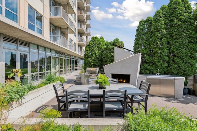 929 Portland Ave Unit 2510, Minneapolis, MN 55404 - view of patio featuring a warm lit fireplace, outdoor dining space, and exterior kitchen