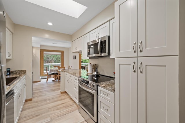 14575 Burma Ave W Unit 306, Rosemount, MN 55068 - kitchen featuring appliances with stainless steel finishes, a skylight, light stone countertops, white cabinetry, and light wood-type flooring