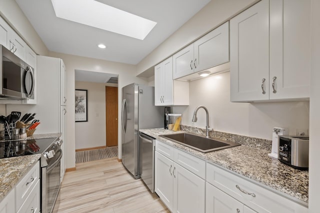 14575 Burma Ave W Unit 306, Rosemount, MN 55068 - kitchen with appliances with stainless steel finishes, a skylight, white cabinets, light stone counters, and light wood-type flooring