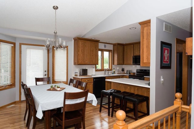 2518 Parkhill Ln SW, Rochester, MN 55902 - kitchen with black appliances, light countertops, vaulted ceiling, brown cabinetry, and decorative backsplash